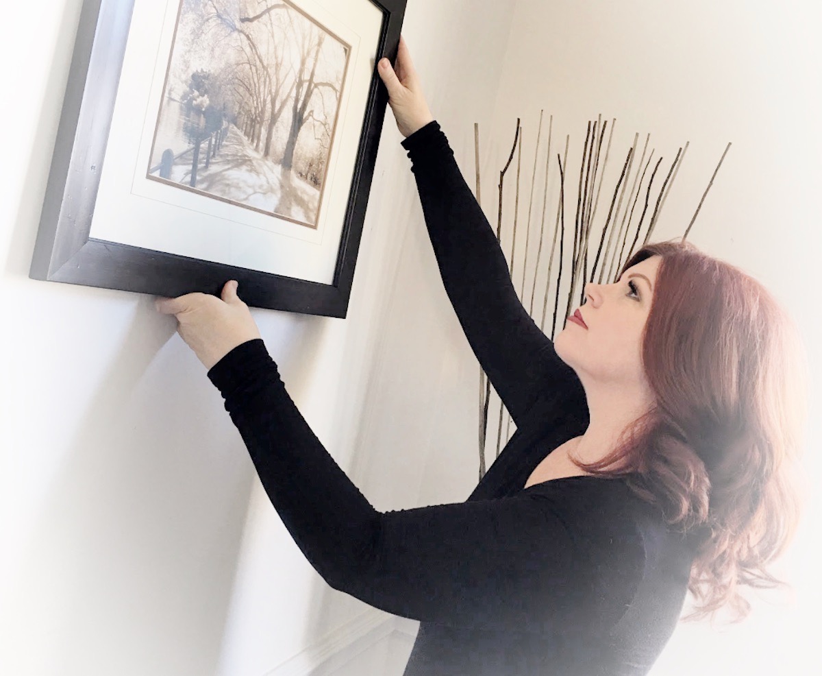 Award Winning Home Stager, Teresa Meyer, at work hanging a black and white print